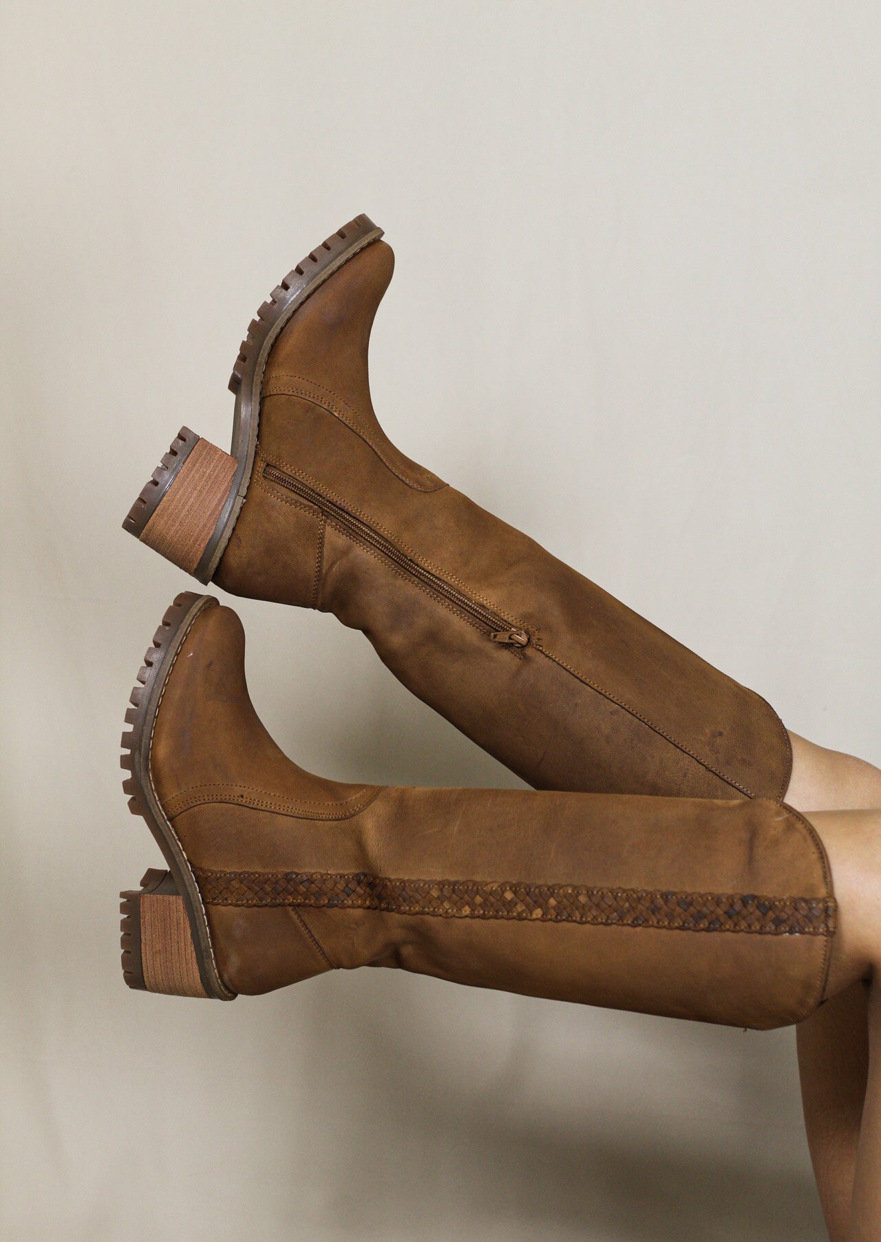 Tan knee-high boots worn, legs crossed