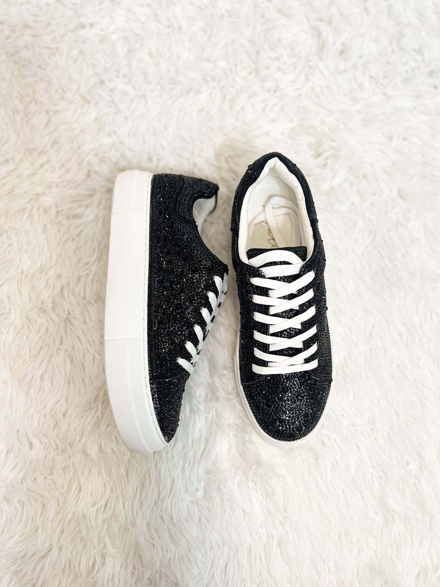 Black rhinestone sneakers flat lay on fur